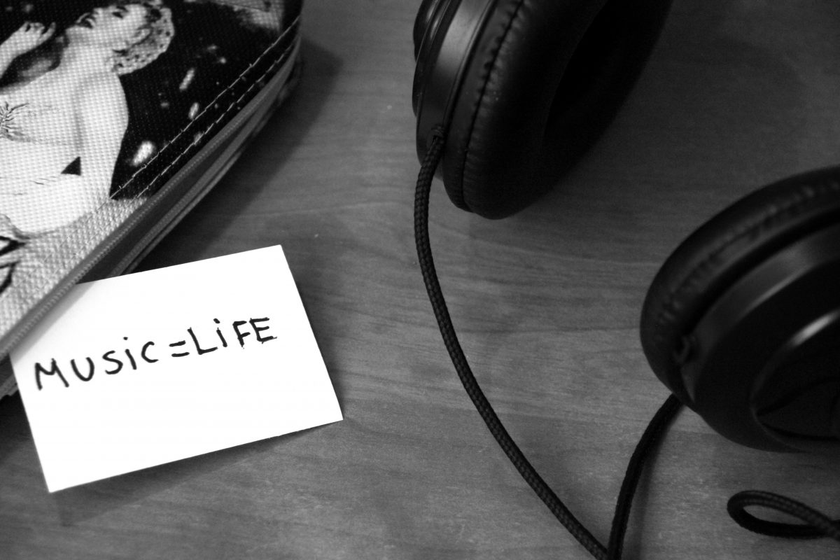A pair of headphones laid on a table, next to a handwritten note that reads "Music equals life".